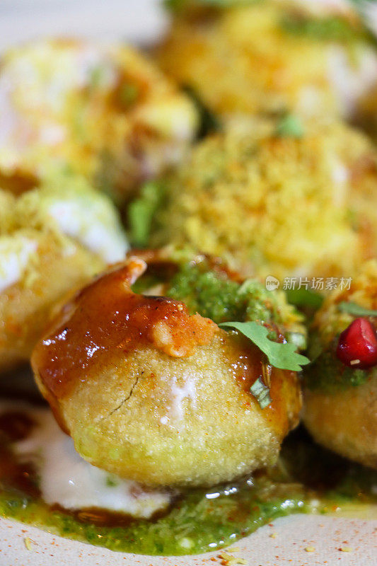 golgappa puri(油炸水球)的全帧图像，中空的酥脆球体，土豆，洋葱，石榴籽和辛辣的酸辣酱，Dahi papri chaat，上面有香草和香料，酸奶，Sev(脆面条)，重点在前景